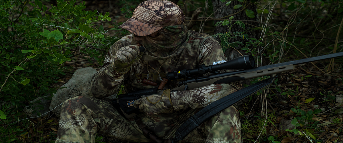 hunter sitting on the ground holding a rifle